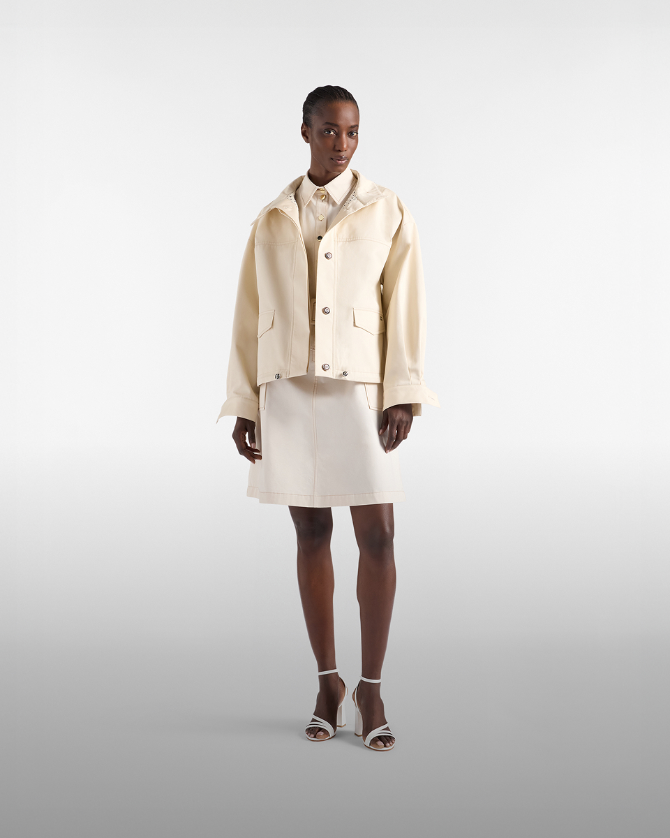 Donna con giacca a vento beige e camicia a righe con cappellino rosa